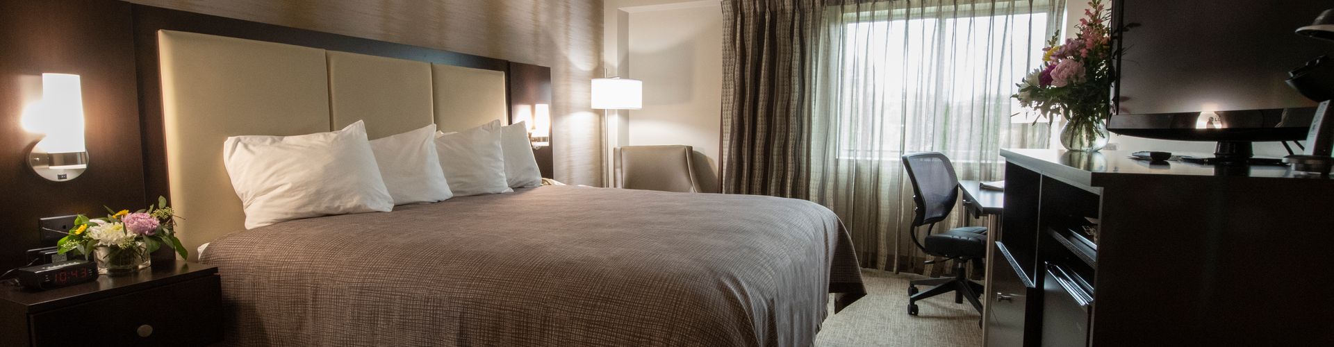 A hotel room with a large bed, desk, and window